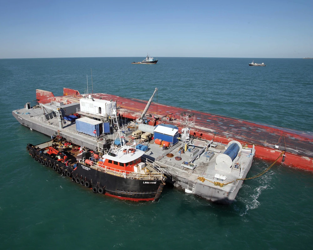 The Lana Rose docks near an upturned shipping vessel